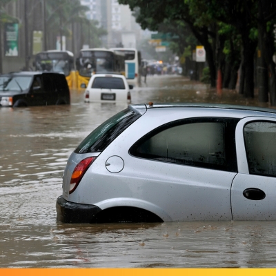 Zalany samochód w czasie powodzi. W tle widać inne samochody i autobusy, które utknęły w wodzie. 